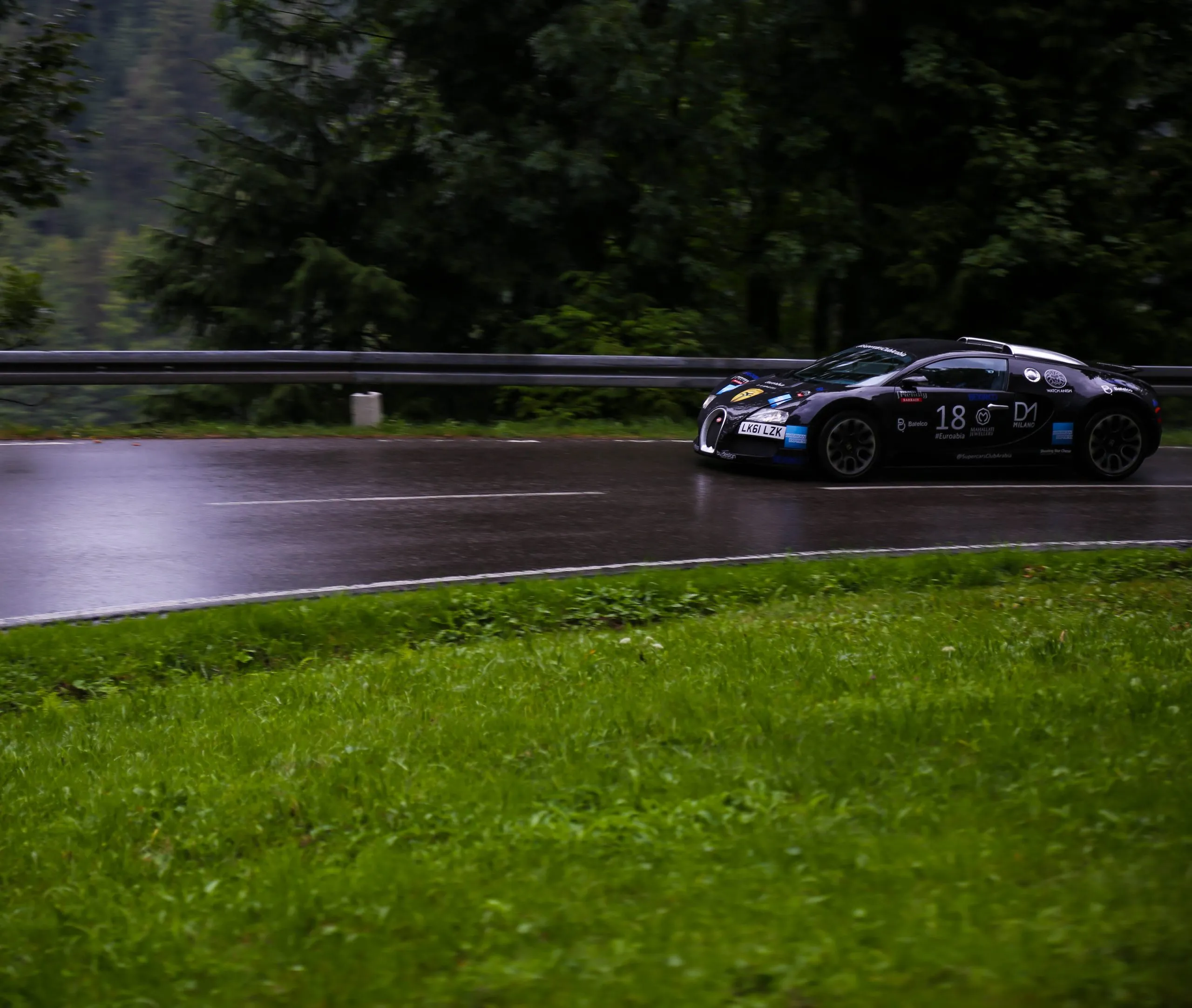 Dark supercar cresting a forest road