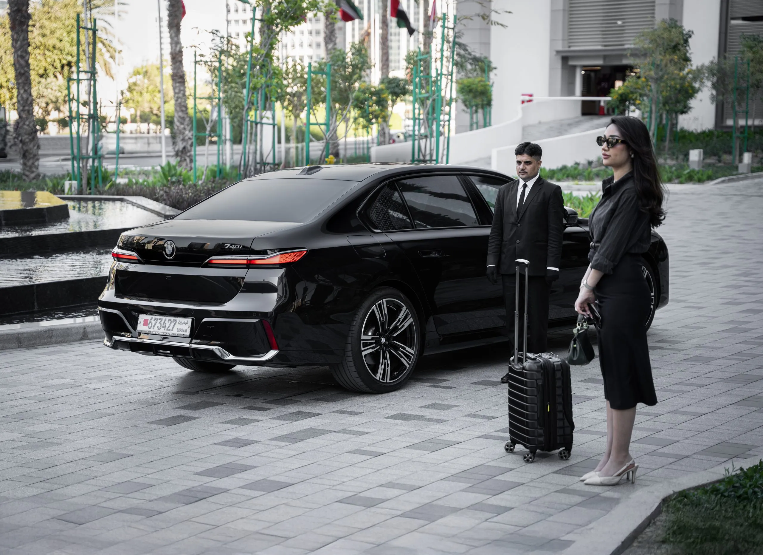 Chauffeur with luggage beside a black sedan