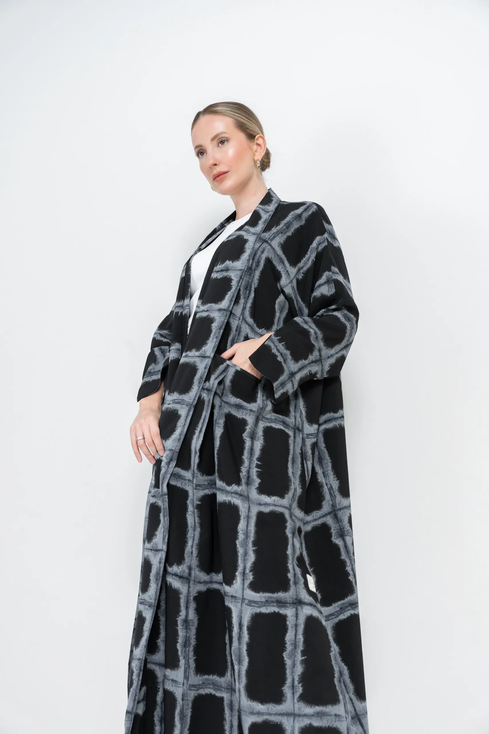 Model in a long checked coat against white
