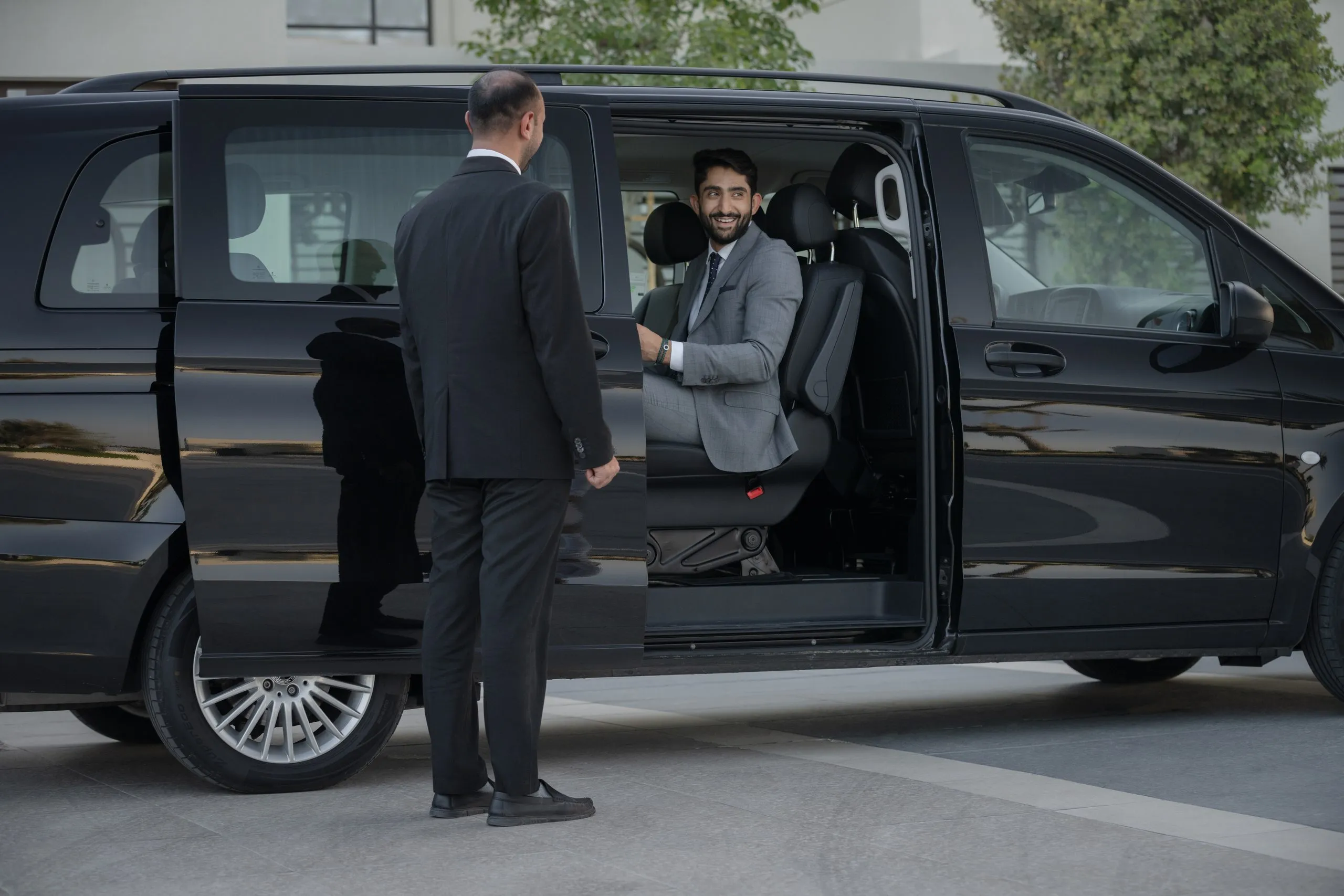 Chauffeur greeting a passenger at a black van