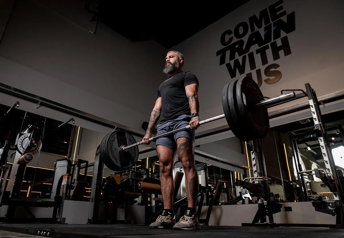 Athlete training with a barbell in a dark gym