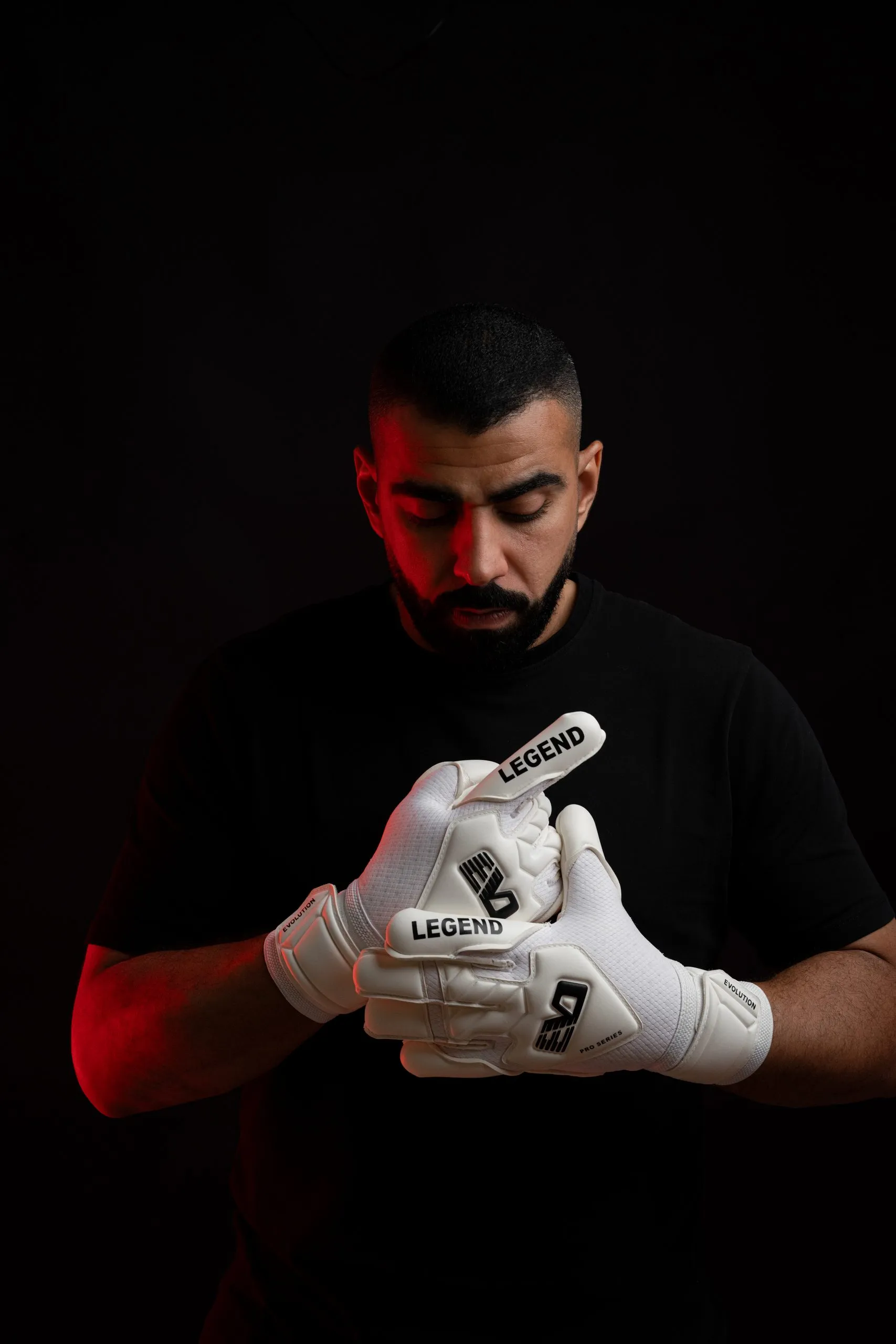 Goalkeeper in black kit and white gloves, studio portrait