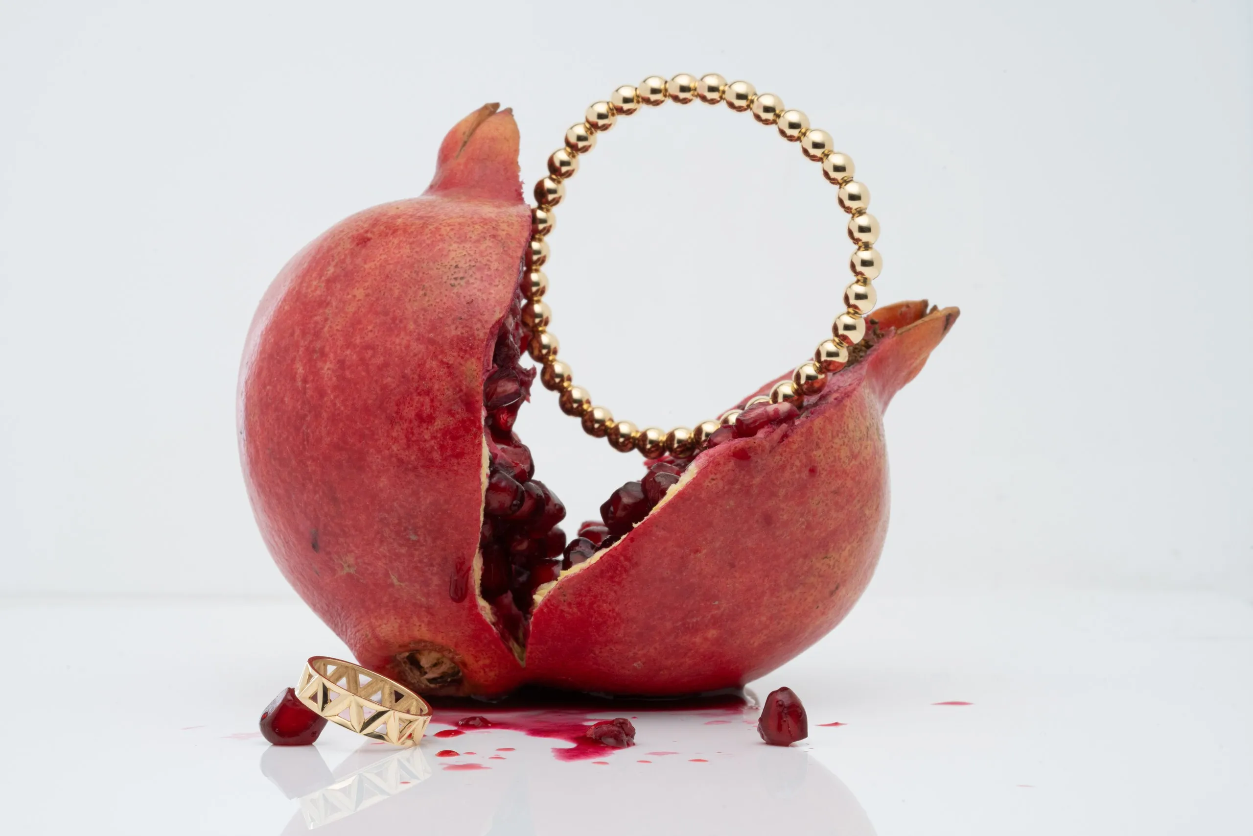 Gold bracelet wrapped around a split pomegranate