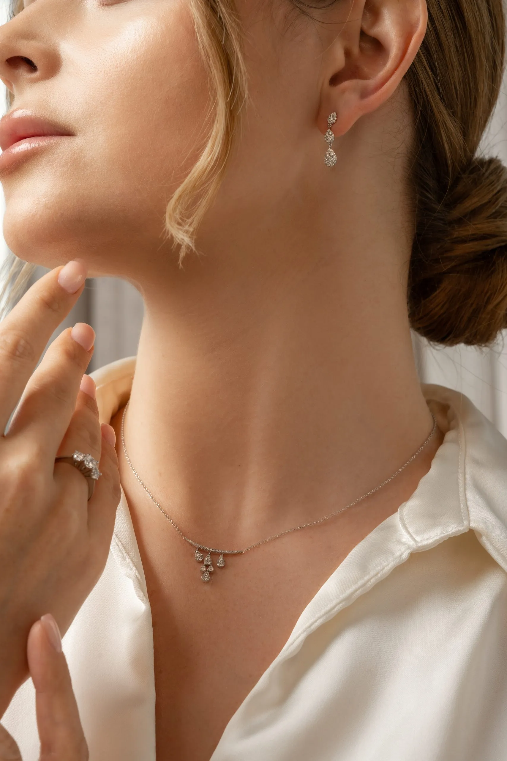 Gold earring and necklace on a woman in a white shirt