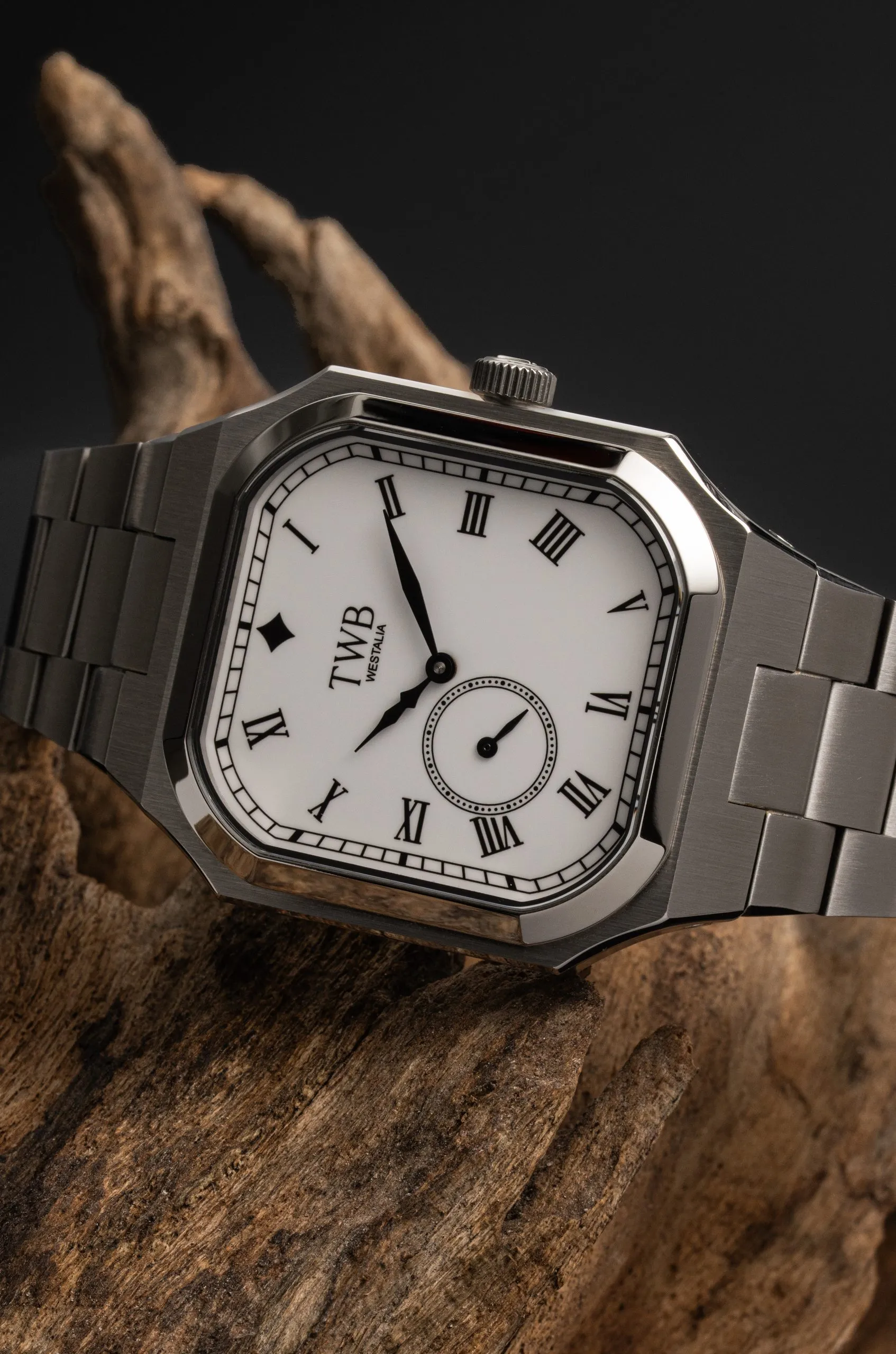 Square silver watch on a wrist in a tweed sleeve