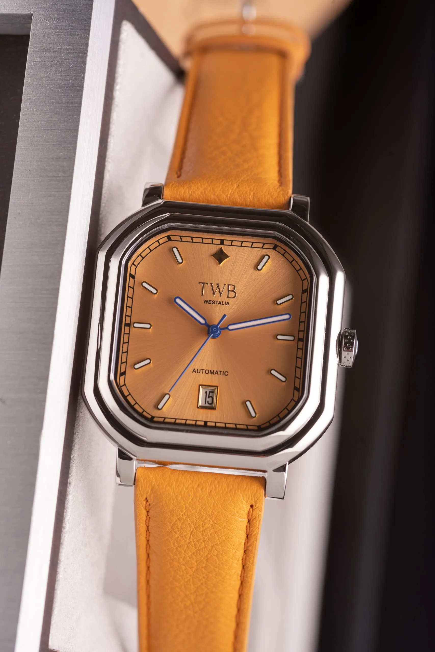 Square watch on an orange leather strap