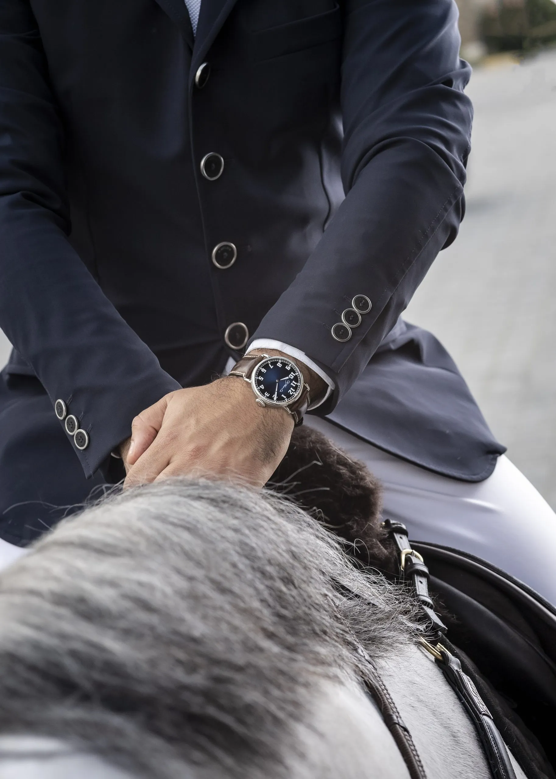 Man in a navy suit adjusting his watch