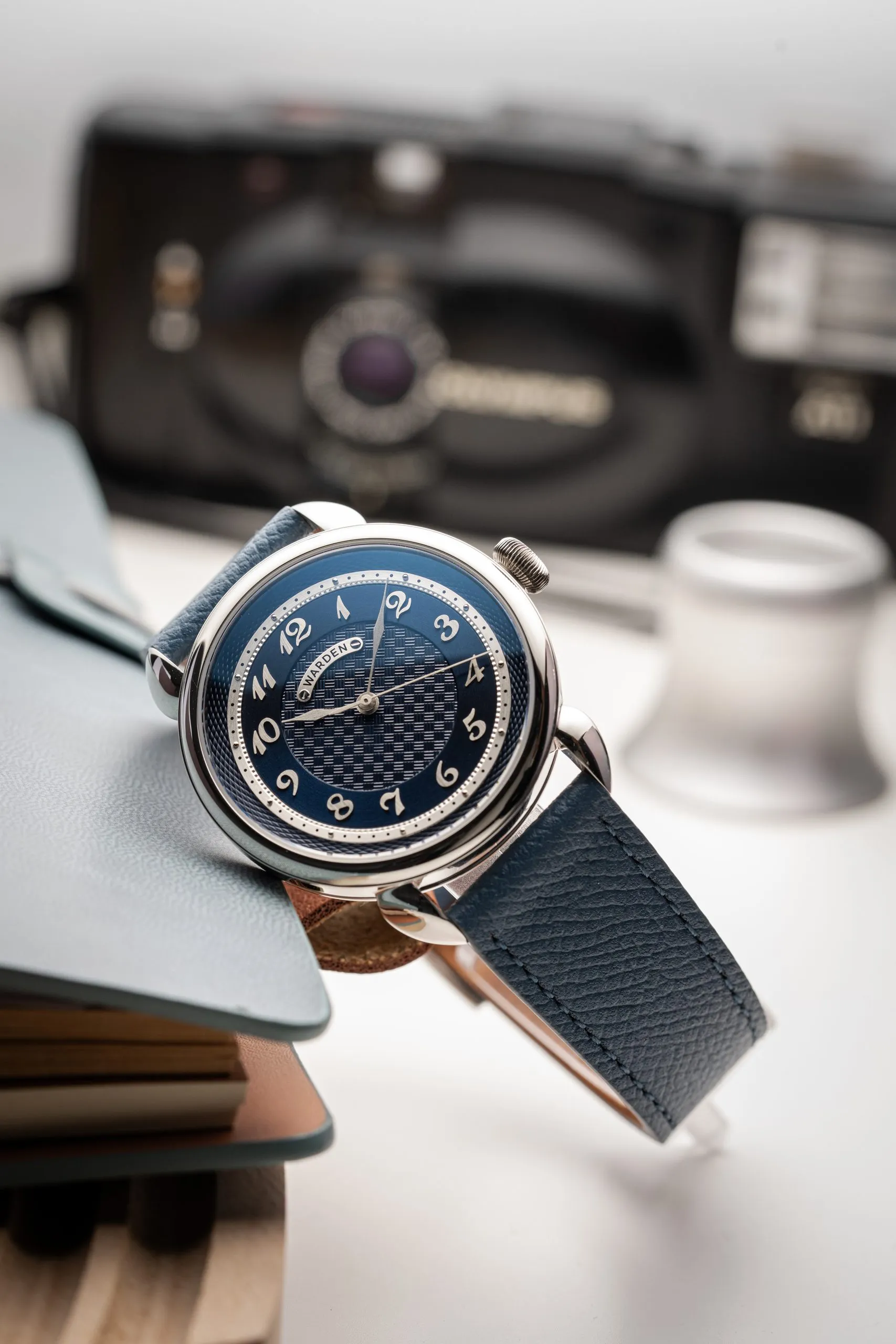 Watch with a black strap beside a vintage camera