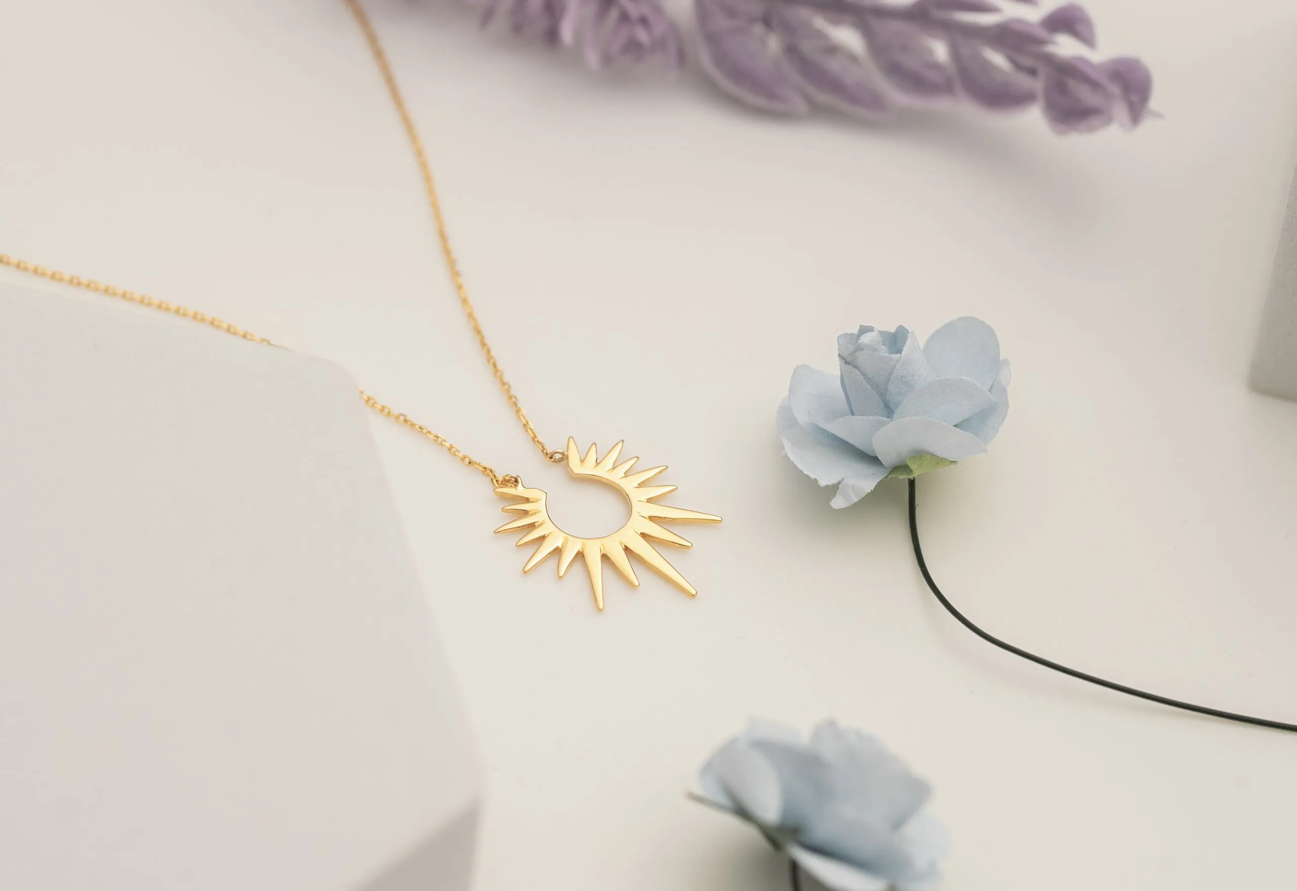 Gold sunburst pendant among dried flowers