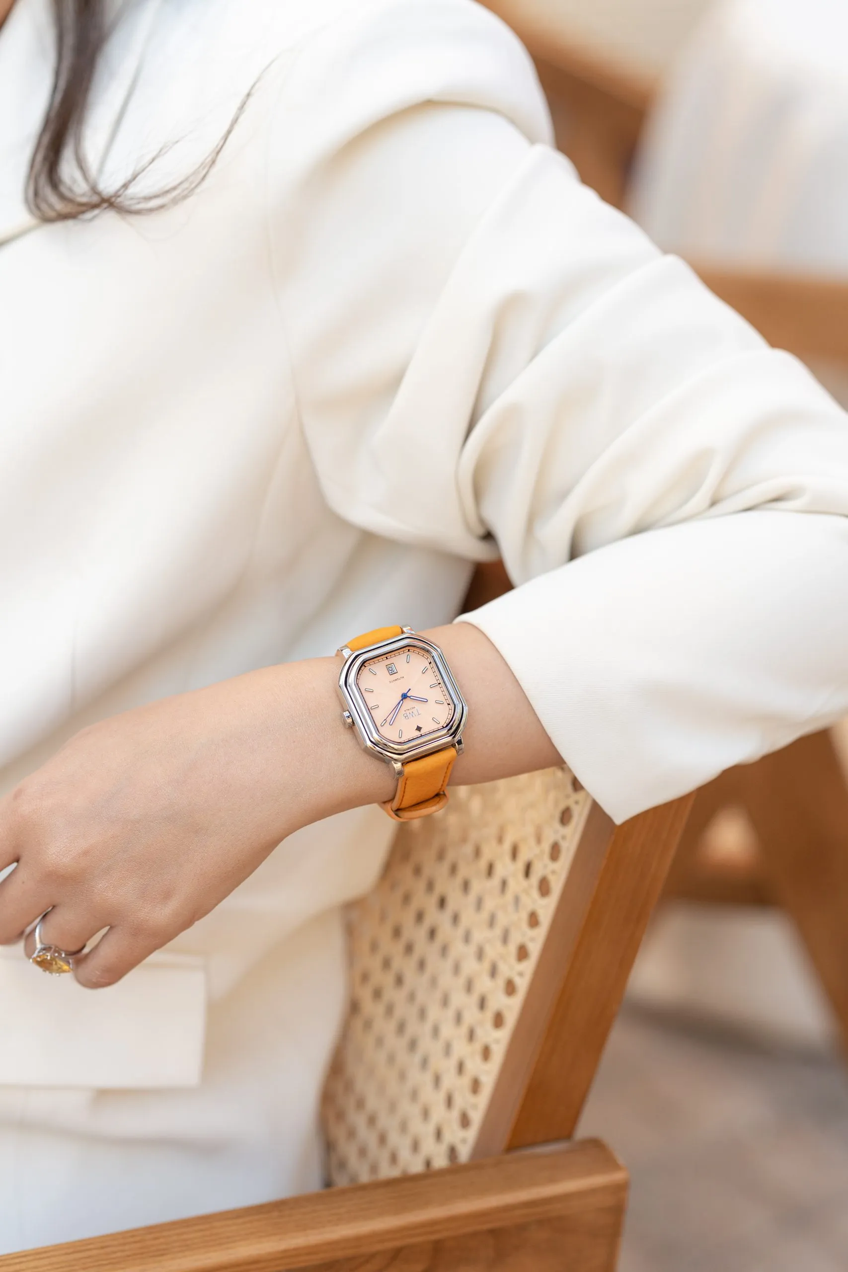 Woman in a cream knit wearing a slim watch
