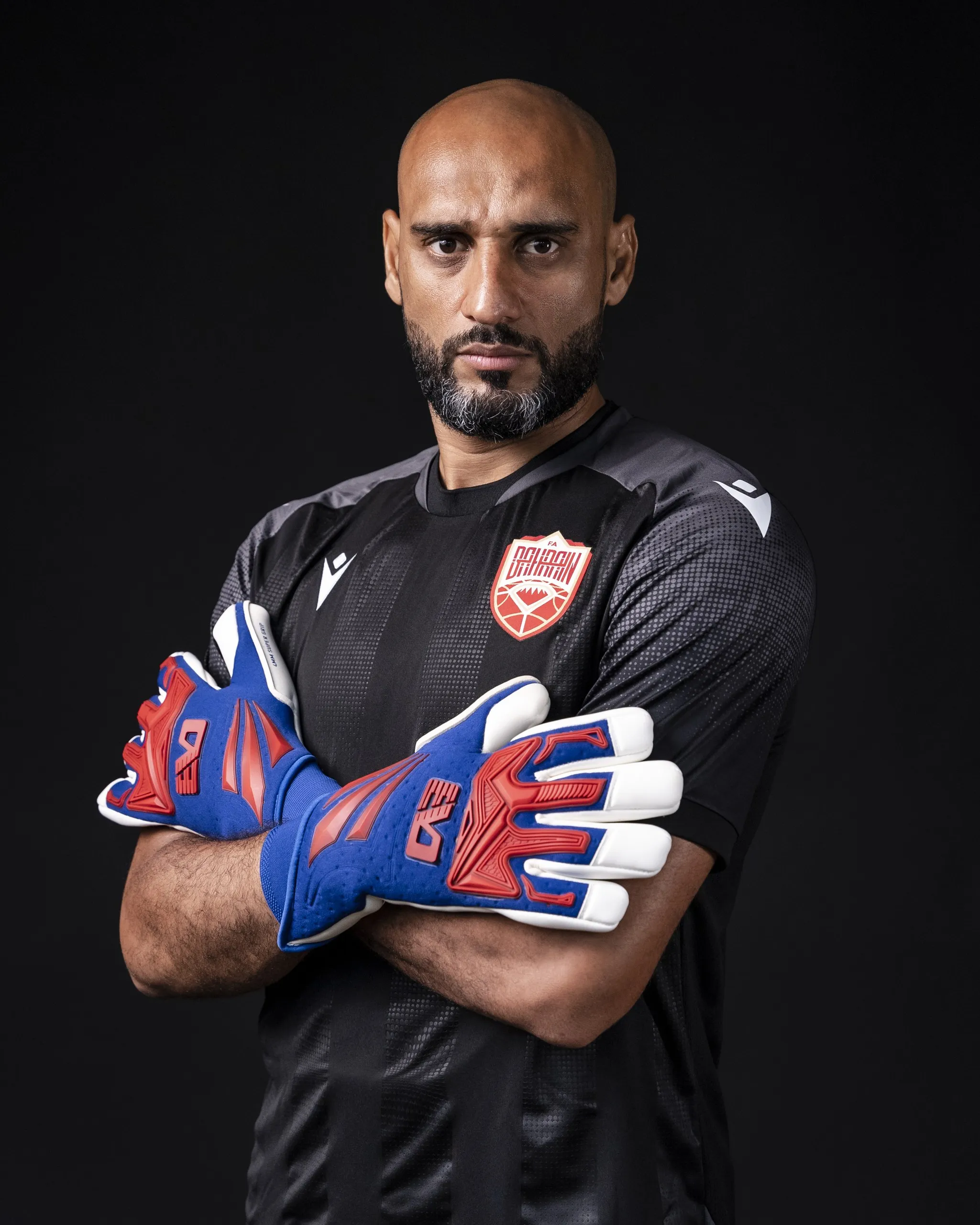 Goalkeeper with arms crossed, lit on black