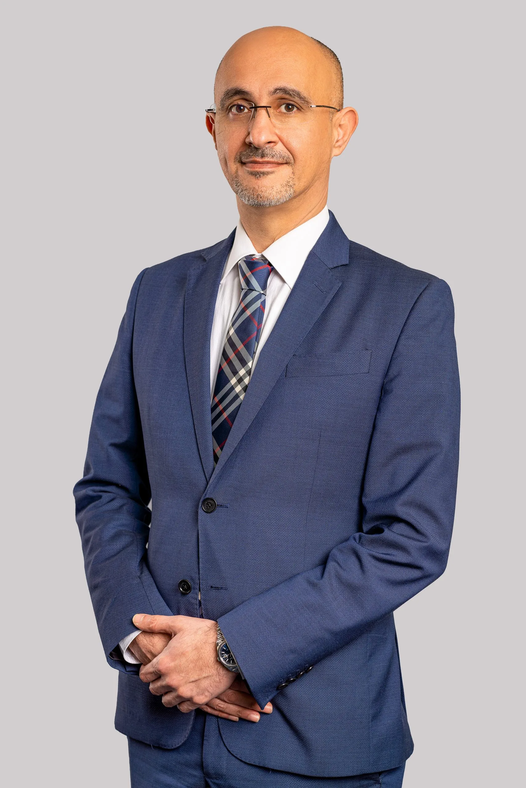 Man in a navy three piece suit on a grey backdrop